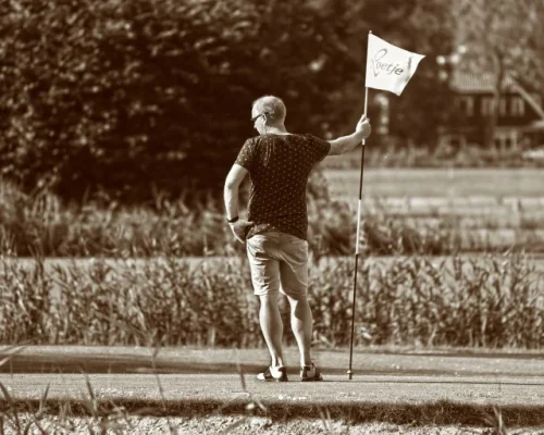 Man with flagstick waiting for slow player